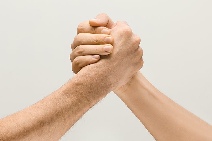 Friends greetings sign or disagreement. Two male hands competion in arm wrestling isolated on grey studio background. Concept of standoff, support, friendship, business, community, strained relations.
